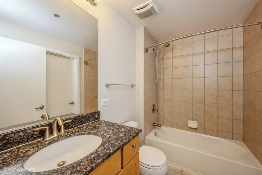 520 South State Street, Unit 702 Chicago, IL 60605 - Photo 14 of 20 a bathroom with a granite countertop bathtub shower sink vanity mirror and toilet