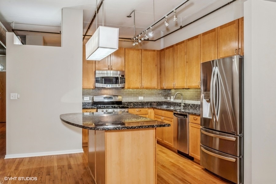 520 South State Street, Unit 702 Chicago, IL 60605 - Photo 7 of 20 a kitchen with stainless steel appliances granite countertop a refrigerator a stove and a sink with wooden floor