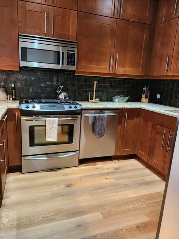 a kitchen with stainless steel appliances granite countertop a stove a sink and a microwave