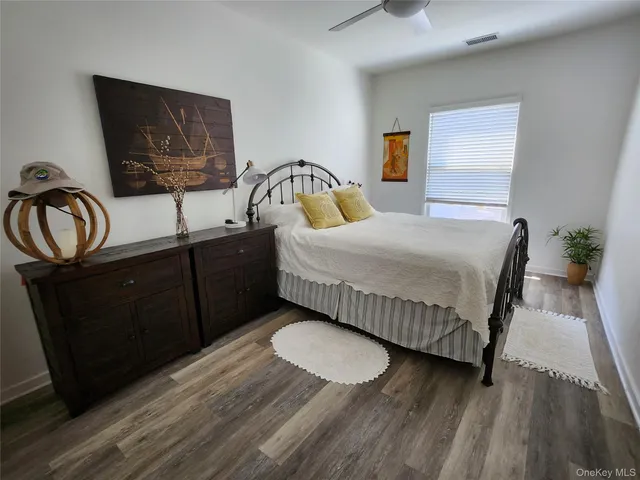a bedroom with a bed and dresser with wooden floor