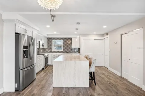 a kitchen with stainless steel appliances granite countertop a refrigerator a sink dishwasher a stove and a refrigerator with wooden floor