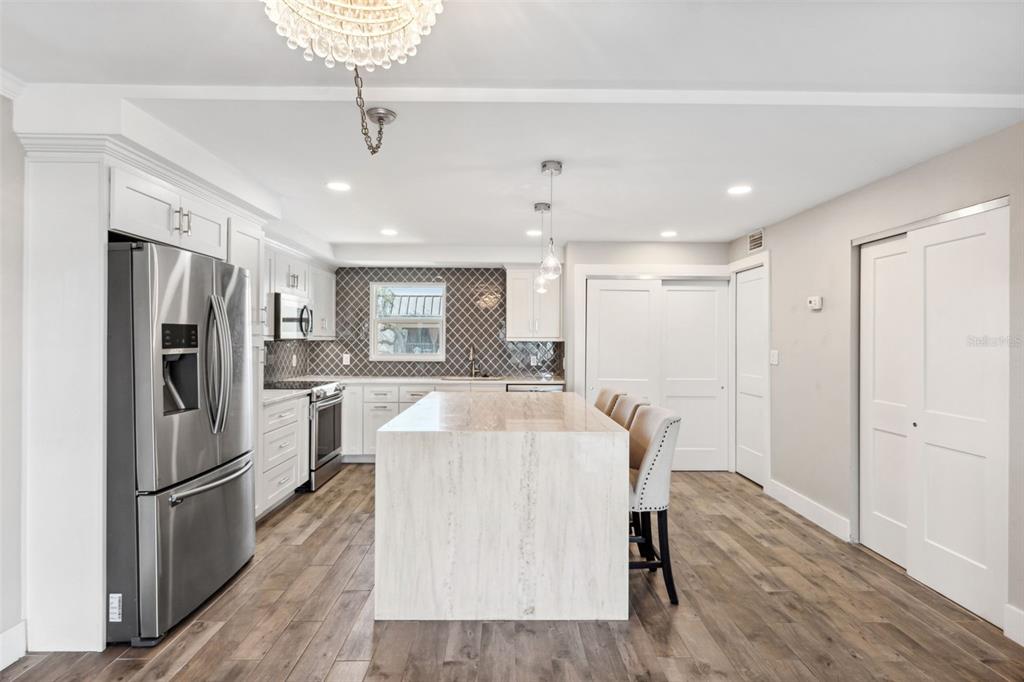 105 4th Avenue Northeast, Unit 418 St. Petersburg, FL 33701 - Photo 5 of 42 a large white kitchen with a refrigerator a stove a sink dishwasher a oven with white cabinets and wooden floor