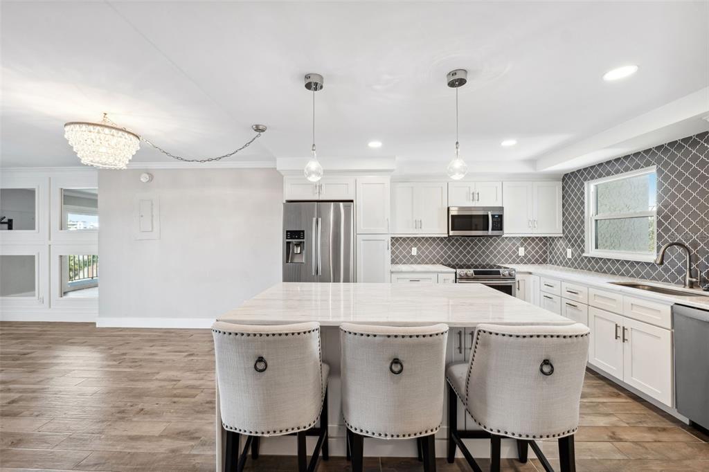 105 4th Avenue Northeast, Unit 418 St. Petersburg, FL 33701 - Photo 7 of 42 a kitchen with stainless steel appliances granite countertop a sink a stove a refrigerator a dining table and chairs with wooden floor