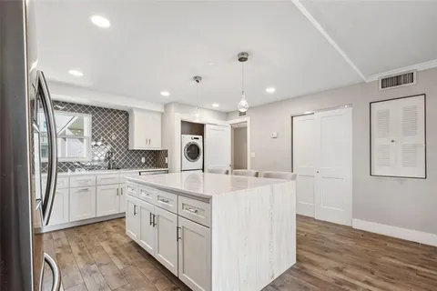a large white kitchen with stainless steel appliances granite countertop a stove and a refrigerator
