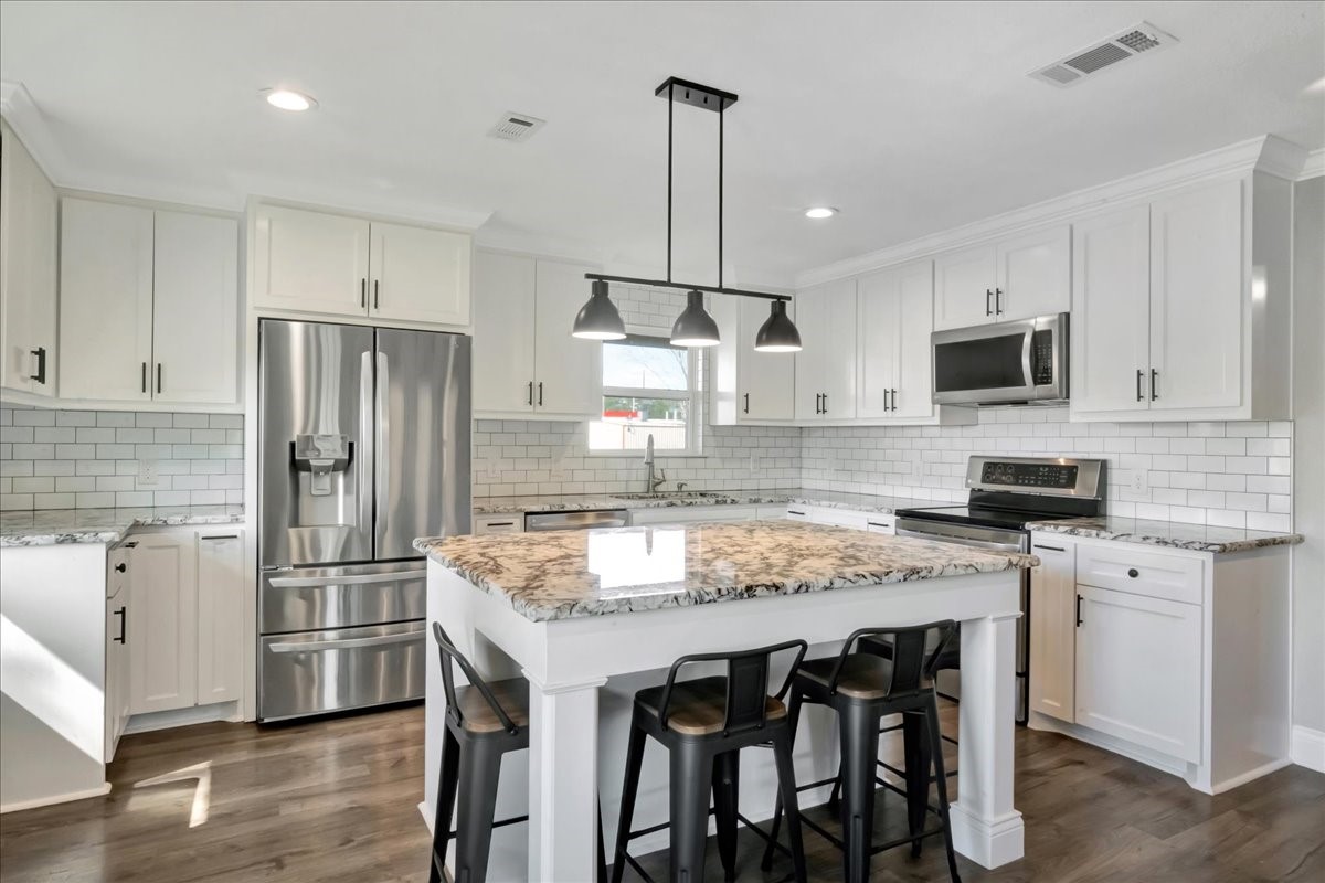 12335 2nd Street Santa Fe, TX 77539 - Photo 15 of 49 a kitchen with stainless steel appliances granite countertop a table chairs stove microwave and refrigerator