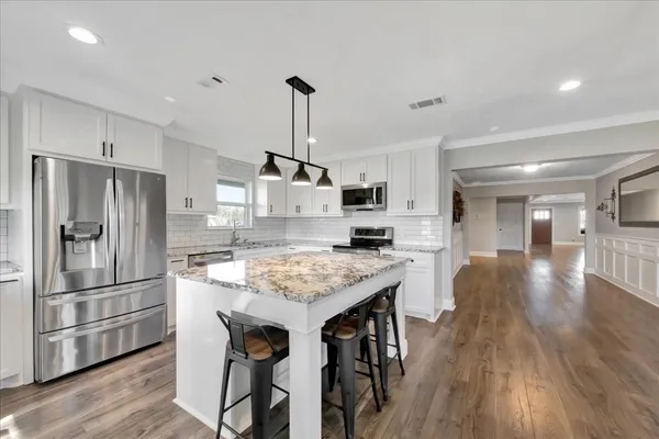 a kitchen with stainless steel appliances granite countertop a table chairs stove and refrigerator