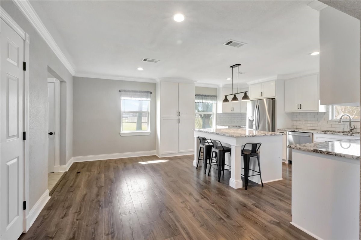 12335 2nd Street Santa Fe, TX 77539 - Photo 20 of 49 a dining room with kitchen island stainless steel appliances furniture wooden floor and a kitchen view