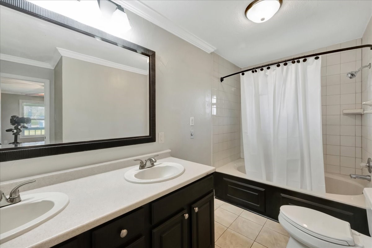 12335 2nd Street Santa Fe, TX 77539 - Photo 29 of 49 a bathroom with a sink a toilet a mirror and shower curtain