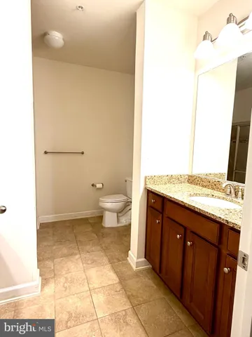 a spacious bathroom with a granite countertop sink a toilet and a mirror