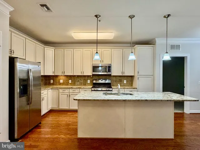 a kitchen with stainless steel appliances granite countertop a sink a refrigerator a stove and a refrigerator