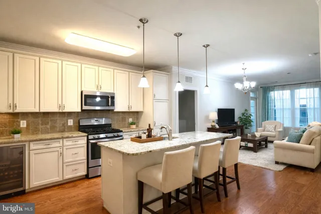 a kitchen with stainless steel appliances kitchen island granite countertop a stove a sink dishwasher a refrigerator with white cabinets and wooden floor