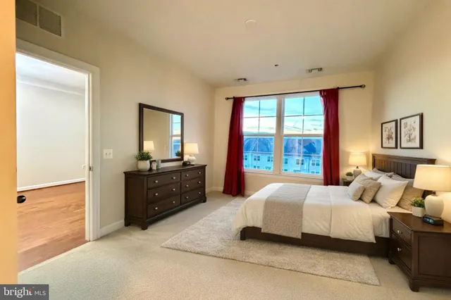 a spacious bedroom with a large bed and a dresser next to a window