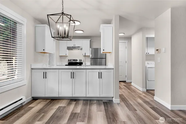 a kitchen with kitchen island granite countertop a stove a sink and white cabinets with wooden floor