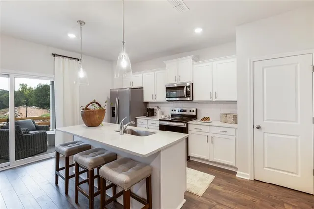 a kitchen that has a table chairs appliances and cabinets