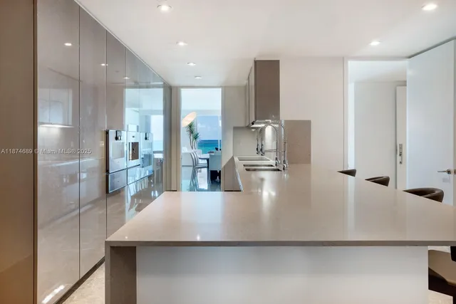 a large kitchen with stainless steel appliances a large counter top a refrigerator and cabinets