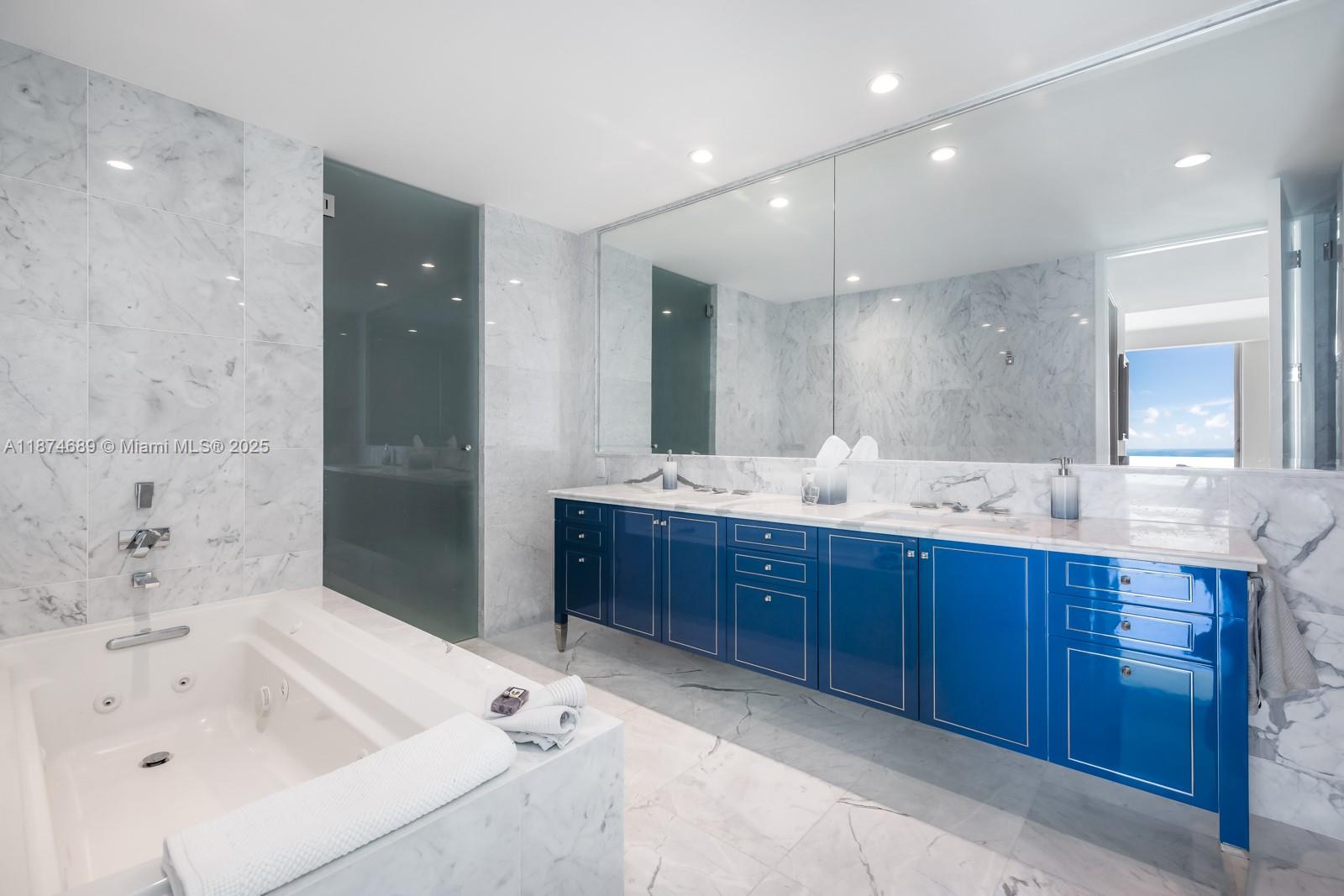 9349 Collins Avenue, Unit 403 Surfside, FL 33154 - Photo 5 of 9 a bathroom with a tub sink double vanity and a mirror