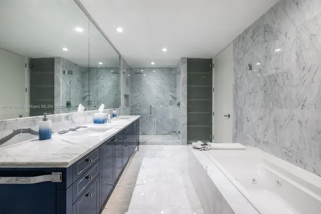 a bathroom with a granite countertop double vanity sink a mirror and a bathtub