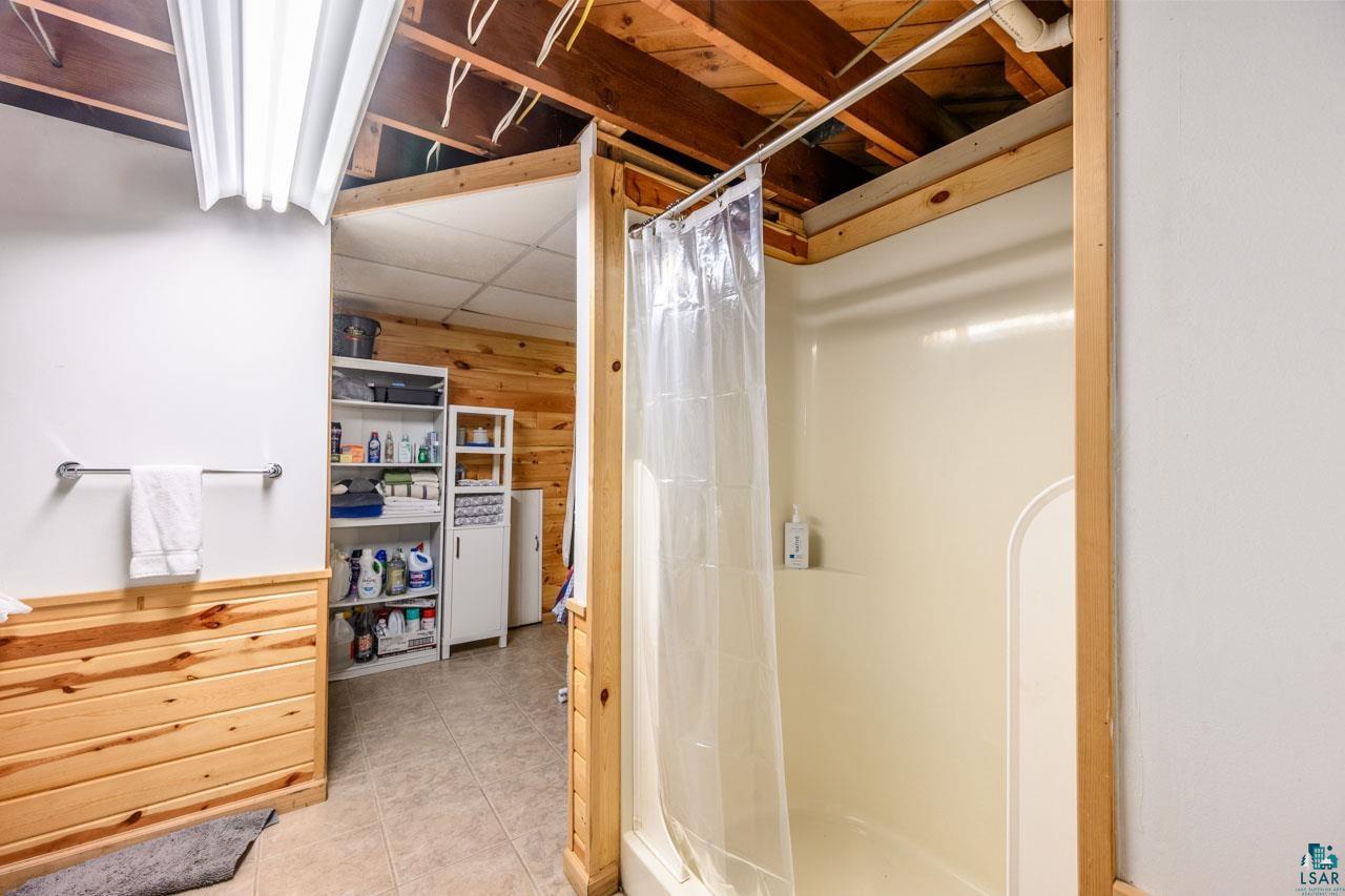 716 South 9th Street Virginia, MN 55792 - Photo 25 of 43 Enclosed shower with a clear shower curtain, wood paneling, and tile flooring