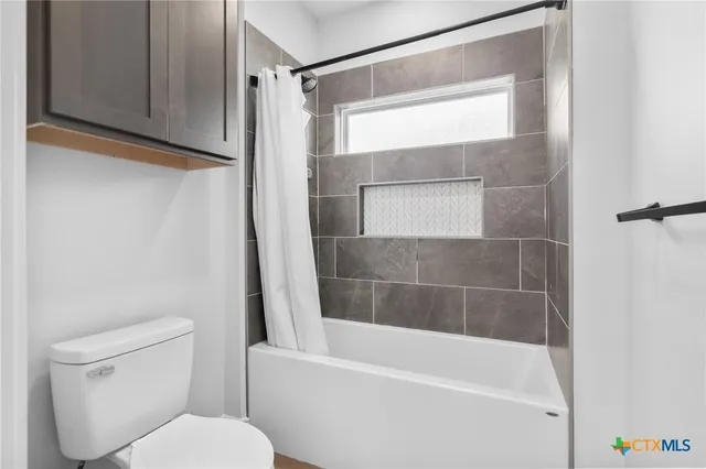 a white toilet sitting next to a bath tub