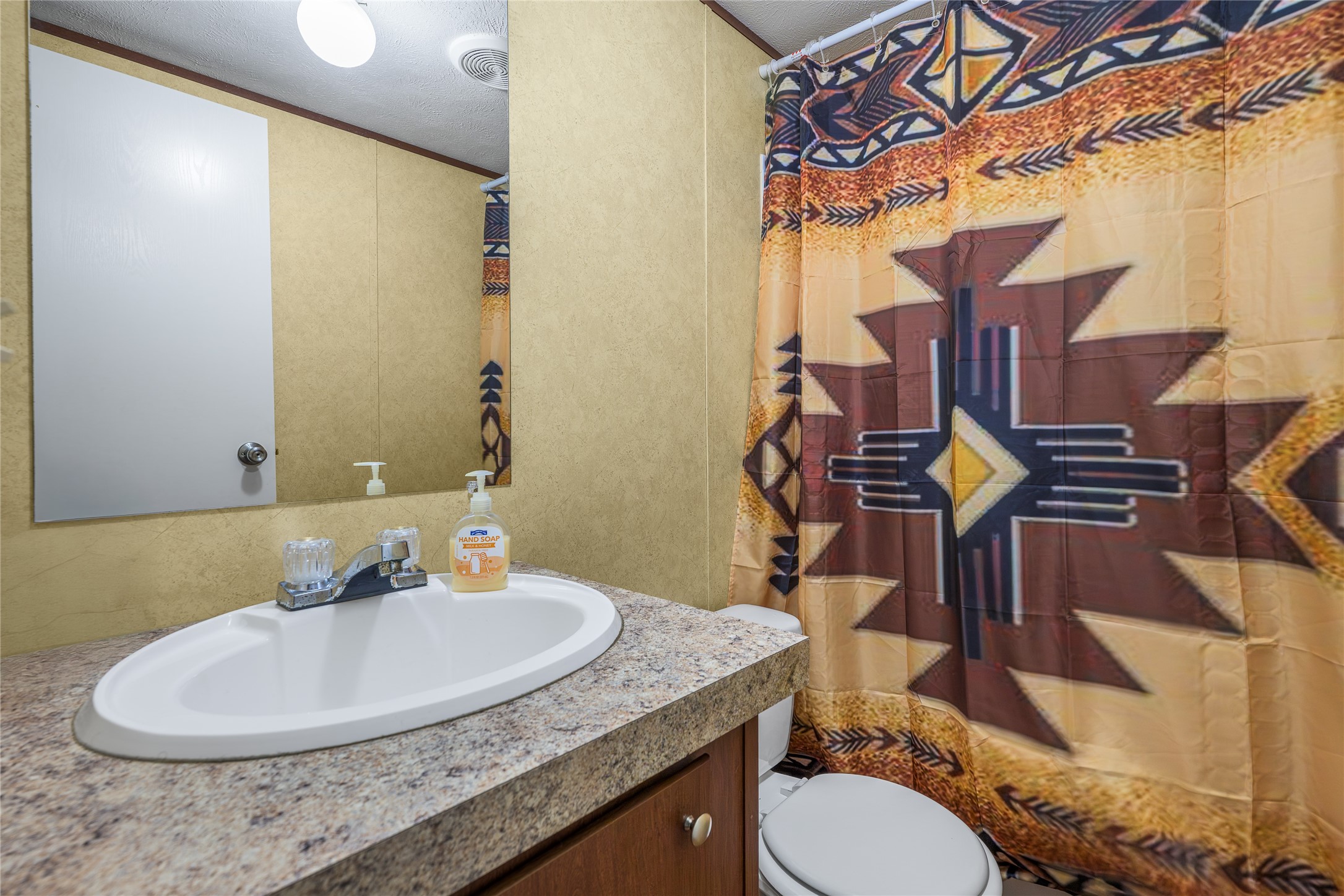 3940 Davis Road West Point, TX 78963 - Photo 16 of 22 a bathroom with a granite countertop sink a toilet and a mirror