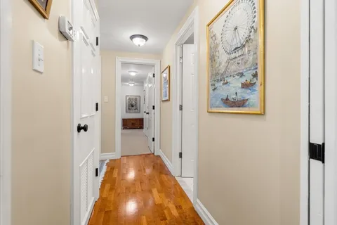 a view of a hallway with wooden floor and a bathroom