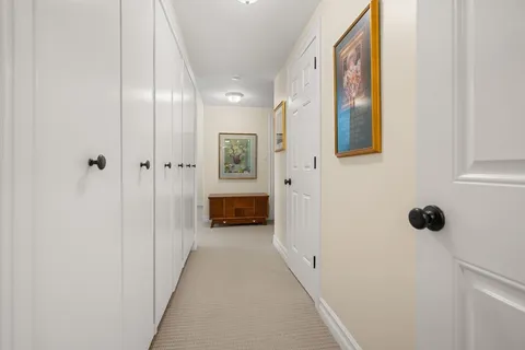 a view of a hallway with wooden floor and a bathroom