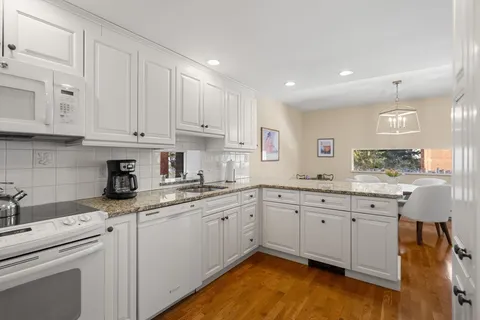 a kitchen with granite countertop white cabinets and white appliances