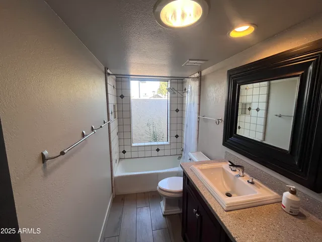 a bathroom with a toilet a sink a tub and mirror