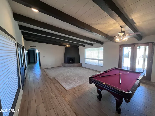 a living room with furniture pool table wooden floor and windows