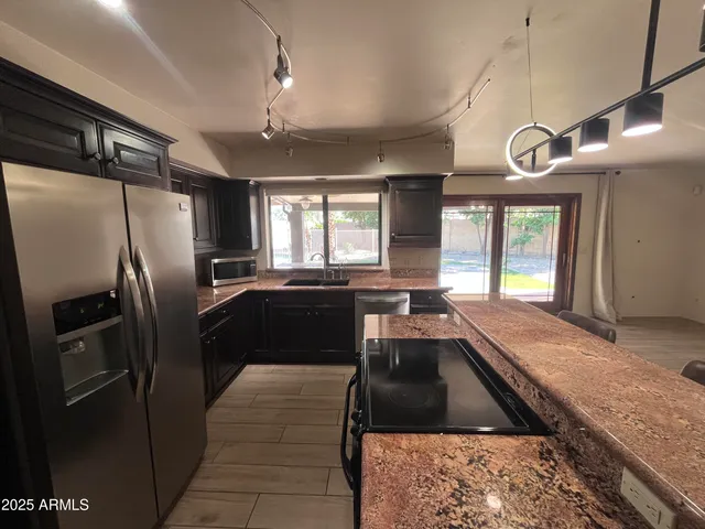 a kitchen with granite countertop stainless steel appliances a refrigerator a sink a stove and cabinets