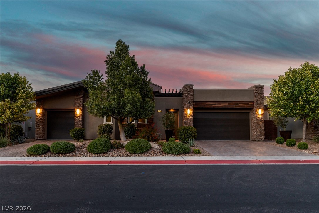 6014 Willow Ridge Court Las Vegas, NV 89135 - Photo 98 of 99 This captivating home presents a harmonious blend of stone and stucco, illuminated by evening lights.