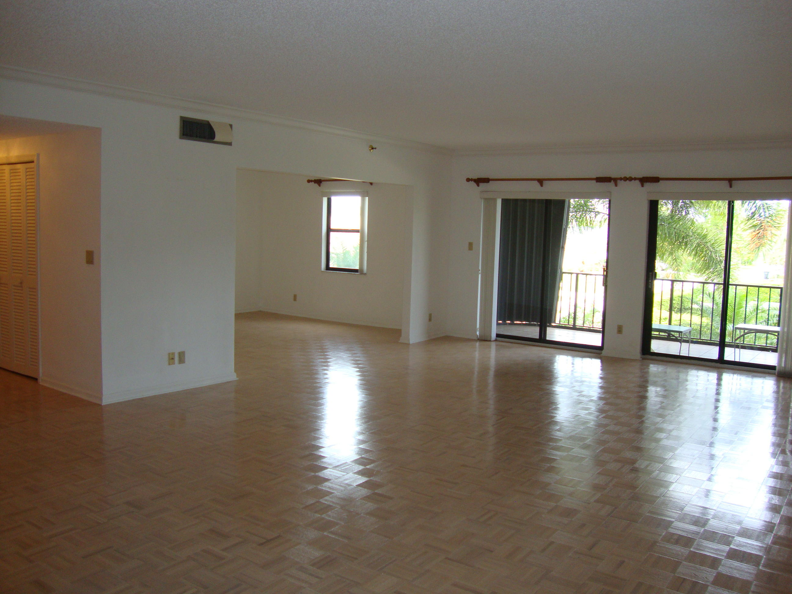 2679 South Ocean Boulevard, Unit 2B Boca Raton, FL 33432 - Photo 4 of 42 an empty room with wooden floor and windows with curtains