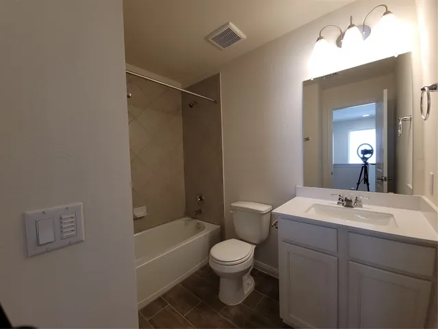 a bathroom with a toilet sink vanity tub and mirror