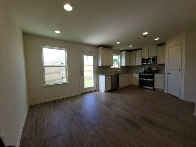 an open kitchen with kitchen island wooden floors appliances and cabinets