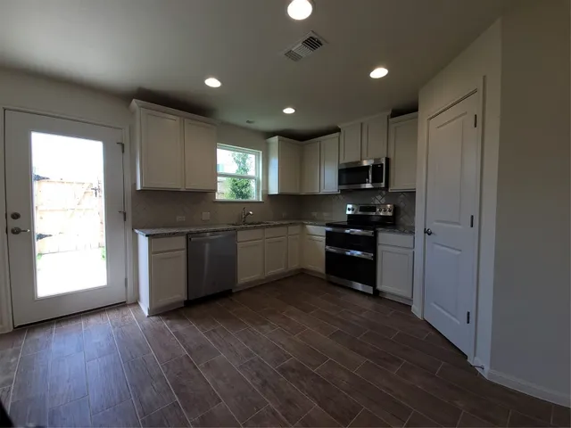 a kitchen with granite countertop a stove a sink and a refrigerator