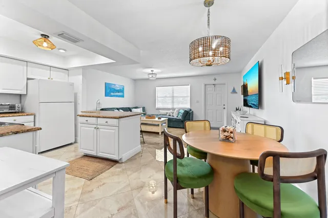 a kitchen with a dining table chairs and a refrigerator