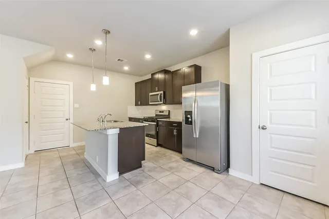a large kitchen with a large counter top stainless steel appliances and cabinets