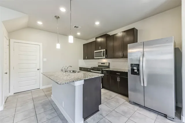 a kitchen with kitchen island granite countertop stainless steel appliances and a sink