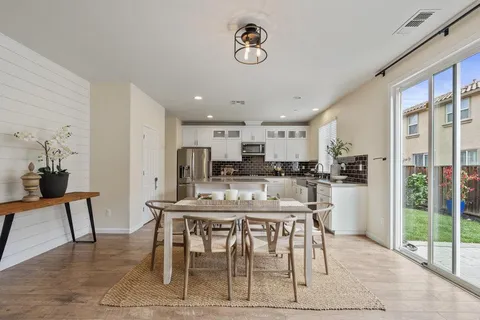 a kitchen with stainless steel appliances granite countertop a table chairs sink refrigerator and microwave