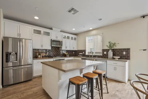 a kitchen with stainless steel appliances granite countertop white cabinets a refrigerator a stove a sink and dishwasher