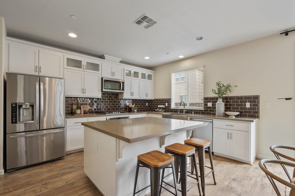 130 Lusitano Way Gilroy, CA 95020 - Photo 16 of 50 a kitchen with stainless steel appliances granite countertop a table chairs sink refrigerator and microwave