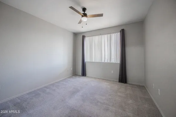 an empty room with windows and ceiling fan