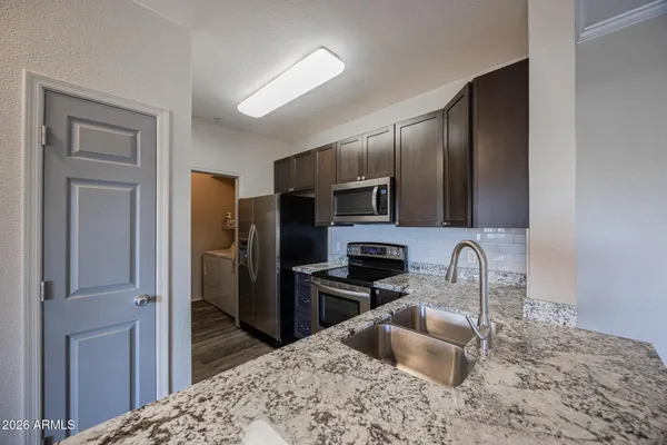 a kitchen with stainless steel appliances granite countertop a refrigerator sink and stove