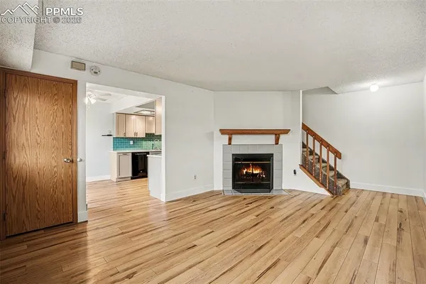 a view of an empty room with wooden floor fireplace and a window