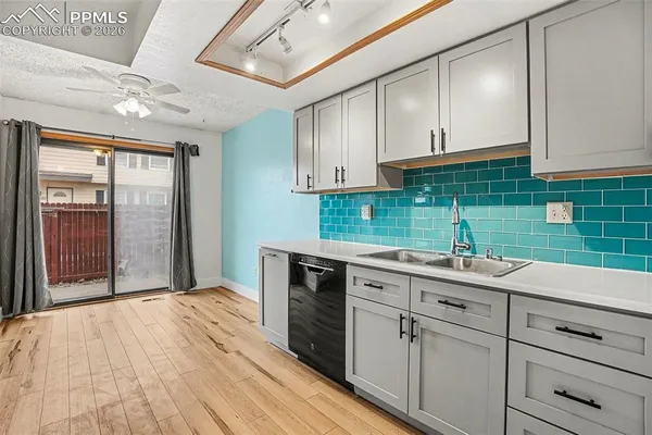 a kitchen with a sink dishwasher a stove and white cabinets with wooden floor