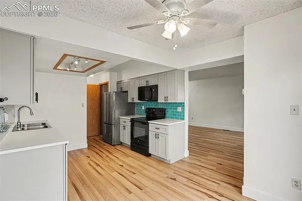 a kitchen with a sink stainless steel appliances a counter top space and cabinets