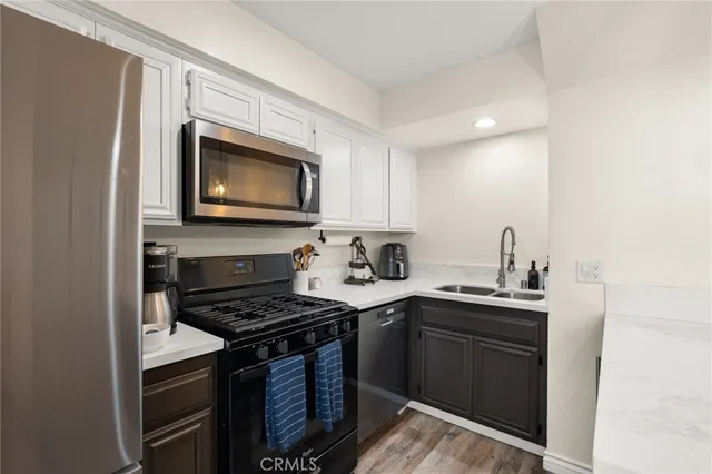 a kitchen with stainless steel appliances kitchen island granite countertop a refrigerator a stove a sink a dining table and chairs with wooden floor