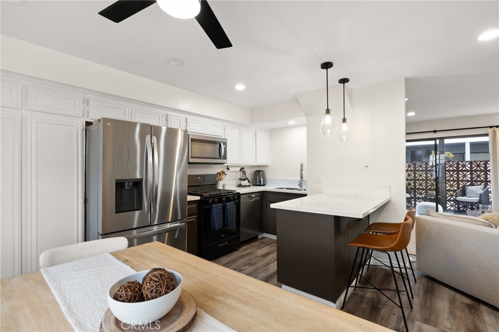 4345 154th Street, Unit 3 Lawndale, CA 90260 - Photo 14 of 31 a kitchen with stainless steel appliances kitchen island granite countertop a refrigerator a stove a sink a dining table and chairs with wooden floor