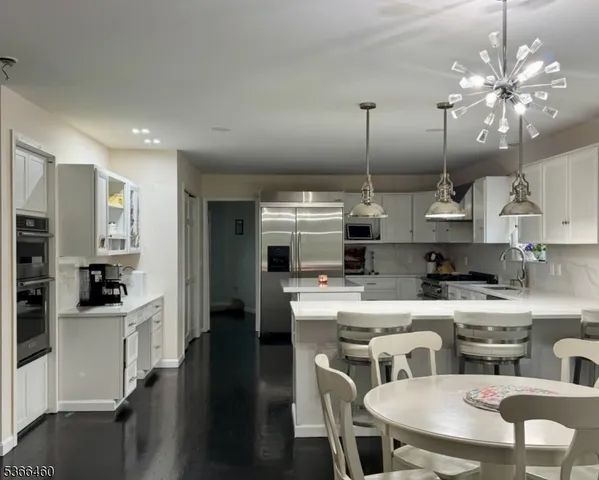 a kitchen with stainless steel appliances kitchen island granite countertop a sink a stove a dining table and chairs