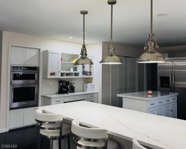 a kitchen with stainless steel appliances kitchen island granite countertop a refrigerator a stove a microwave oven a sink with island and chairs